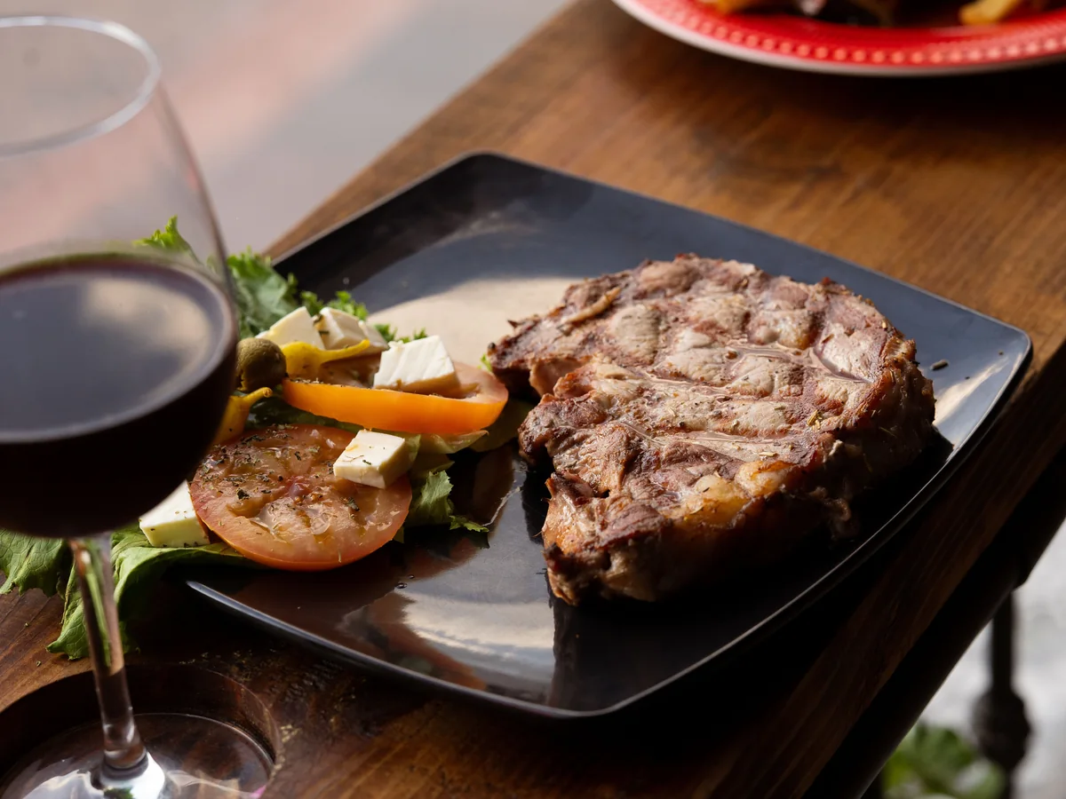 A grilled steak with wine on a restaurant table, representative of the three-course dinner served before the show
